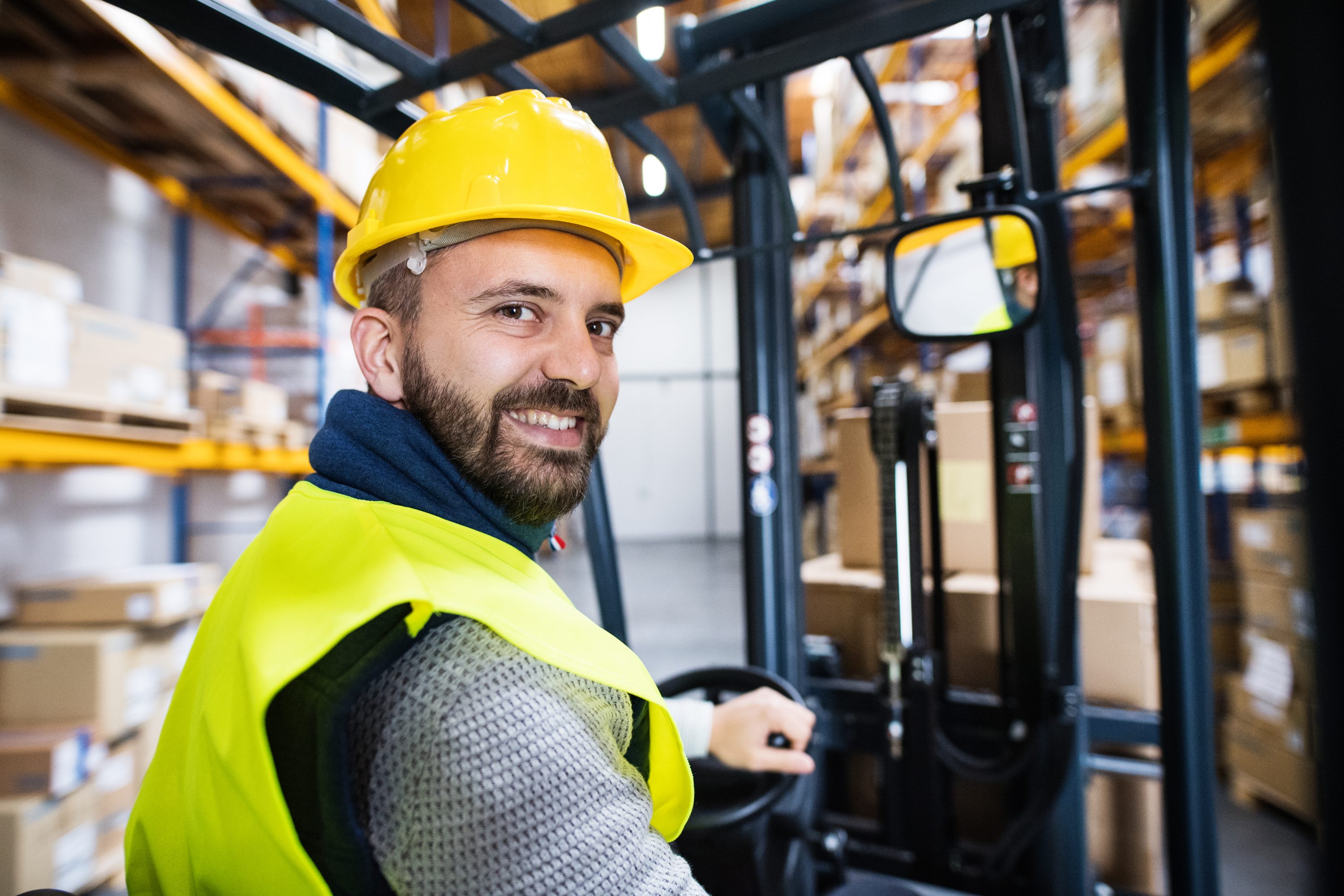Recruitment Agency worker driving high reach Forklift Driver in warehouse.